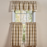 A set of window curtains in a beige and brown plaid pattern, including a Toffee & Elm Layered Valance and Toffee & Elm Plaid Cafe Tiers below, shown hanging on a white window frame against a beige wall.