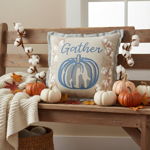 Ashlynn Gather Pumpkin Pillow 12" styled on a rustic wood bench with white and orange pumpkins, fall leaves, and cotton stem branches