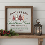 Farm Fresh Christmas Trees wood sign in rustic brown frame displayed on a farmhouse shelf with a lit lantern, pine branches, pinecone, and red plaid bow