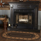 Blackstone Farm Star braided oval rug in black and tan jute placed in front of a black farmhouse fireplace with corrugated metal wall and rustic cabin decor