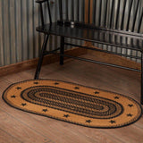 Blackstone Farm Star braided jute rug in black and tan styled in a cabin bedroom with wood floors and rustic decor