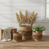 Brinkley Rattan Round Baskets Set of 3 — lifestyle farmhouse view with throw blanket, florals and plant, all three sizes on hardwood floor
