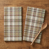 Two Caraway dishtowels with a wooden spoon on a rustic wood table
