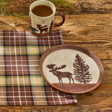 Ceramic plate with moose and pine tree design on a wooden table with a mug of coffee and Friar Brown Plaid Table Runner