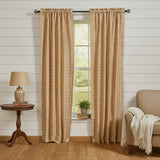 Simmons Plaid red, beige and tan checkered curtain panels hanging on a dark rod in a rustic room with shiplap walls, a side table with a lamp, and a chair with a throw blanket.