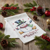 A white kitchen flour sack tea towel featuring a festive snowman wearing a black top hat and a red patterned scarf, holding a glass of red wine. The text 'WINE is cheaper than THERAPY!' is printed below in red and black.