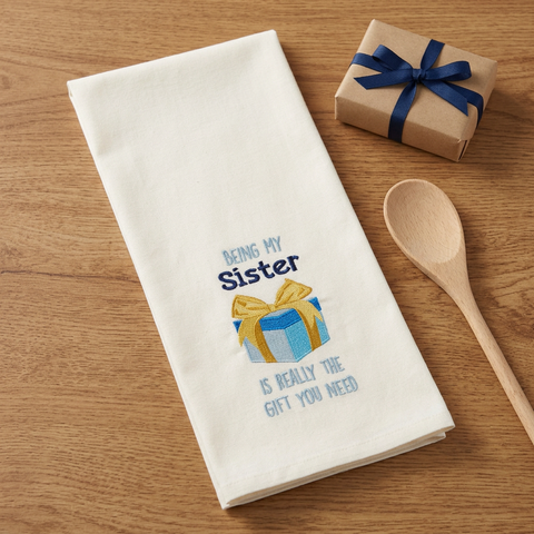 Being My Sister Dishtowel on a wood table with a gift and wooden spoon