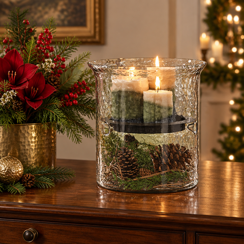 Hammered glass hurricane candle holder beside Christmas florals