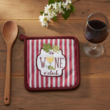 Wine and Dine Pot Holder on a wood table with a wood spoon, a glass of red wine and sprig of white flowers.